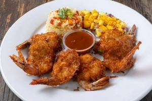 Camarones al coco dorados y crujientes sobre lecho verde