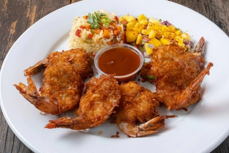 Camarones al coco dorados y crujientes sobre lecho verde