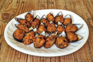 Mejillones rellenos crujientes y dorados sobre una bandeja
