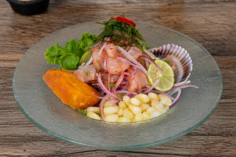 Ceviche de lenguado gourmet decorado con ají limo y cilantro, servido con camote y choclo tierno.