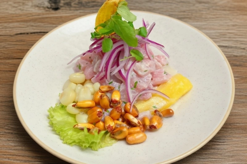 Delicioso Plato de ceviche de reineta fresco con cebolla roja, ají limo, camote y choclo sobre plato