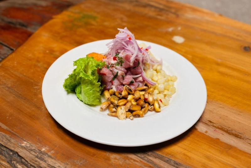 Ceviche de tollo fresco en cubos con cebolla roja, cilantro y ají limo en un plato tradicional.