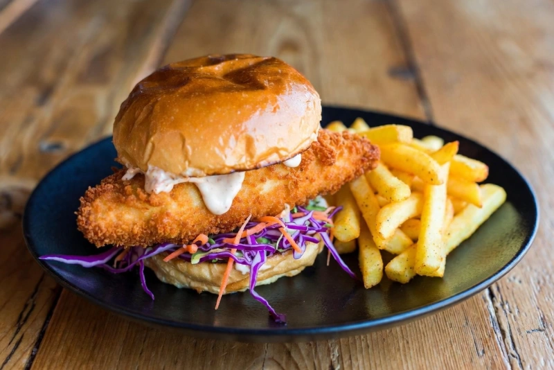 Hamburguesas de pescado caseras doradas en sartén con guarnición de ensalada fresca.